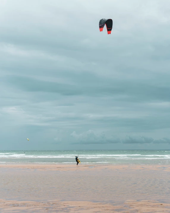 people playing at the beach flying kites