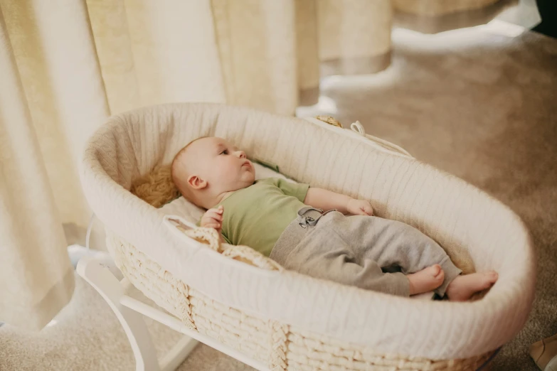 baby lying down in a bassinet for cradle with a blanket