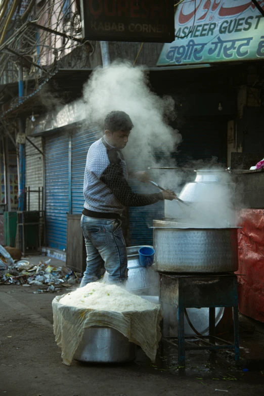 a man standing next to a big pot on a stove