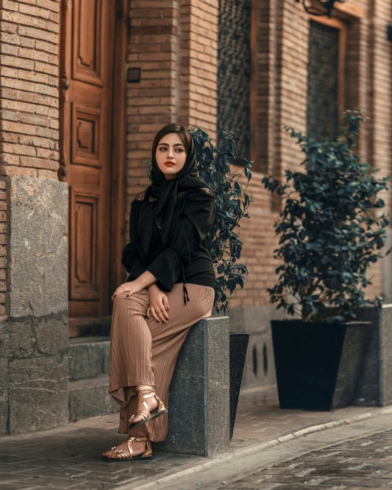 a woman sits on top of a bench next to a planter and a potted tree