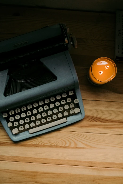 an old fashioned typewriter and candle on a wooden table