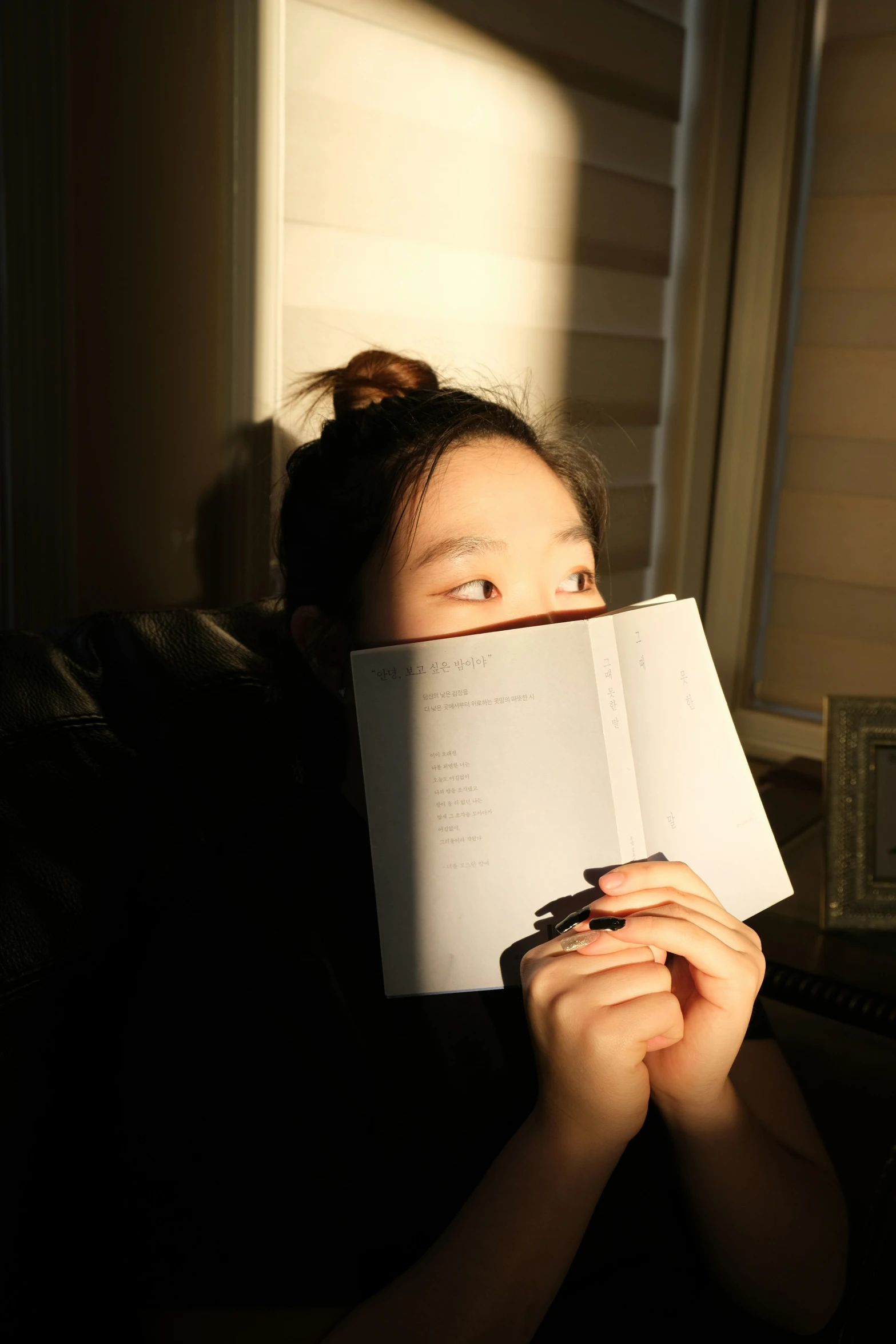 girl peeking over and open up book to see light