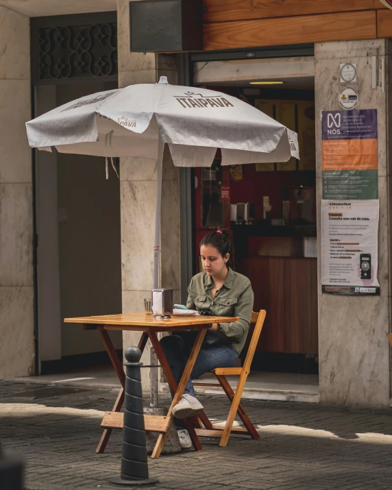 the woman sitting at the table is under an umbrella