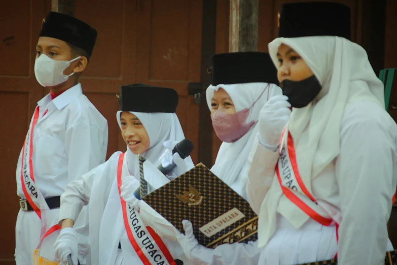 men wearing white headscarves stand together while wearing masks