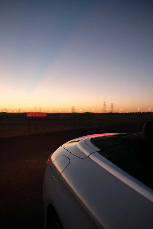 the sun rises behind a power pole in an empty field