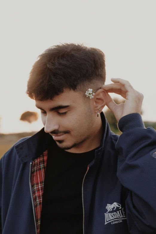 a man looking down and covering his ear with a hand