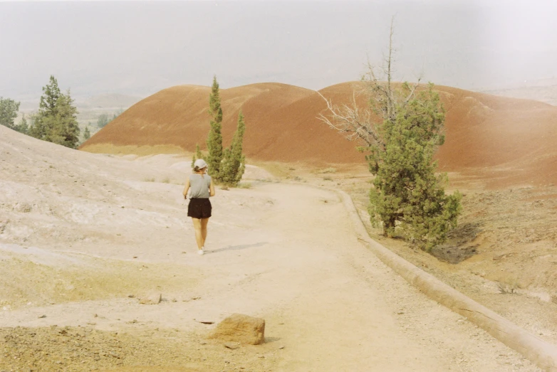 a man walks through the desert near some trees