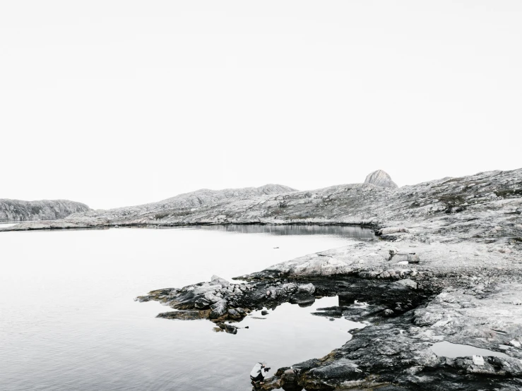 a large lake surrounded by rocks with mountains in the background