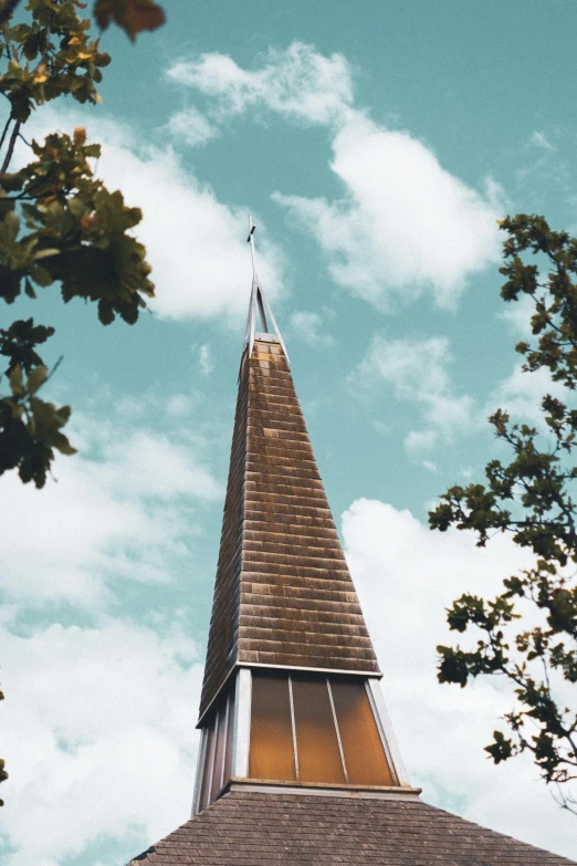 a very tall steeple sitting under a cloudy blue sky