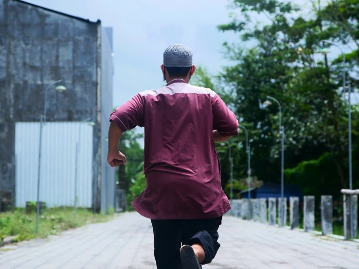 a man with a hat runs down a road