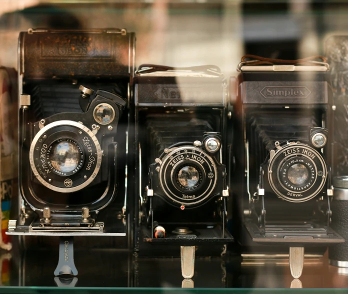 a group of old fashioned cameras with reflection on display