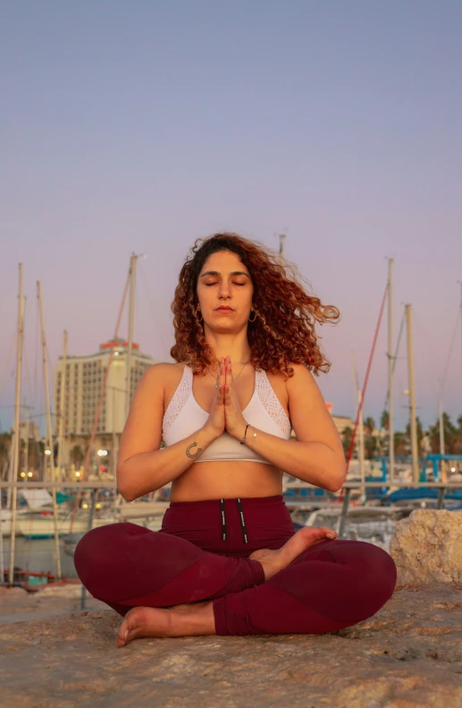 a beautiful woman in a yoga outfit meditating at the beach