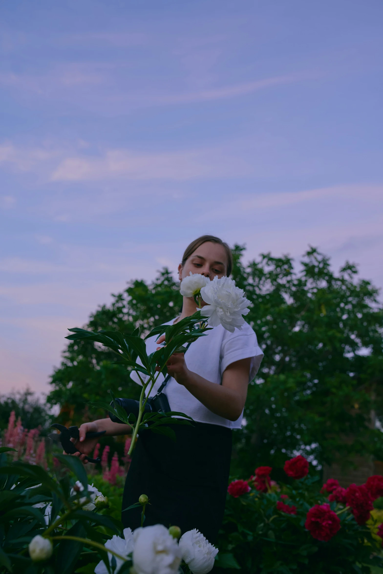 a woman standing in front of flowers holding onto a flower head