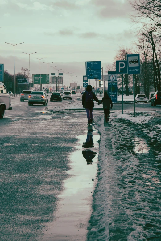 two people walking across the street in snow