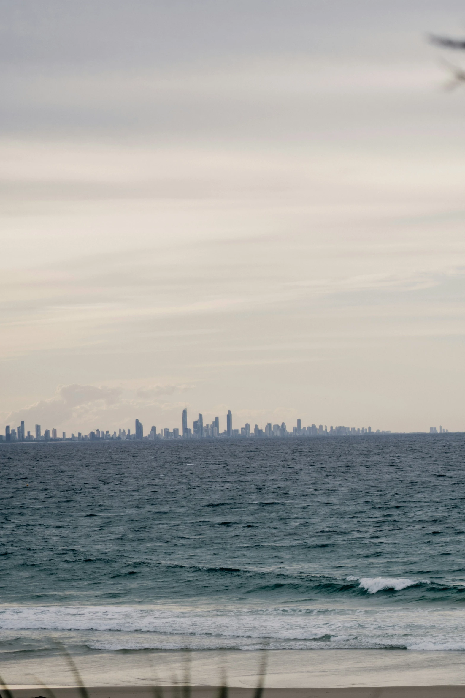 the city skyline is seen across the ocean from a beach