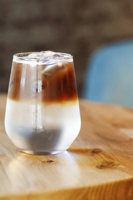 a glass of liquid sitting on top of a wooden table