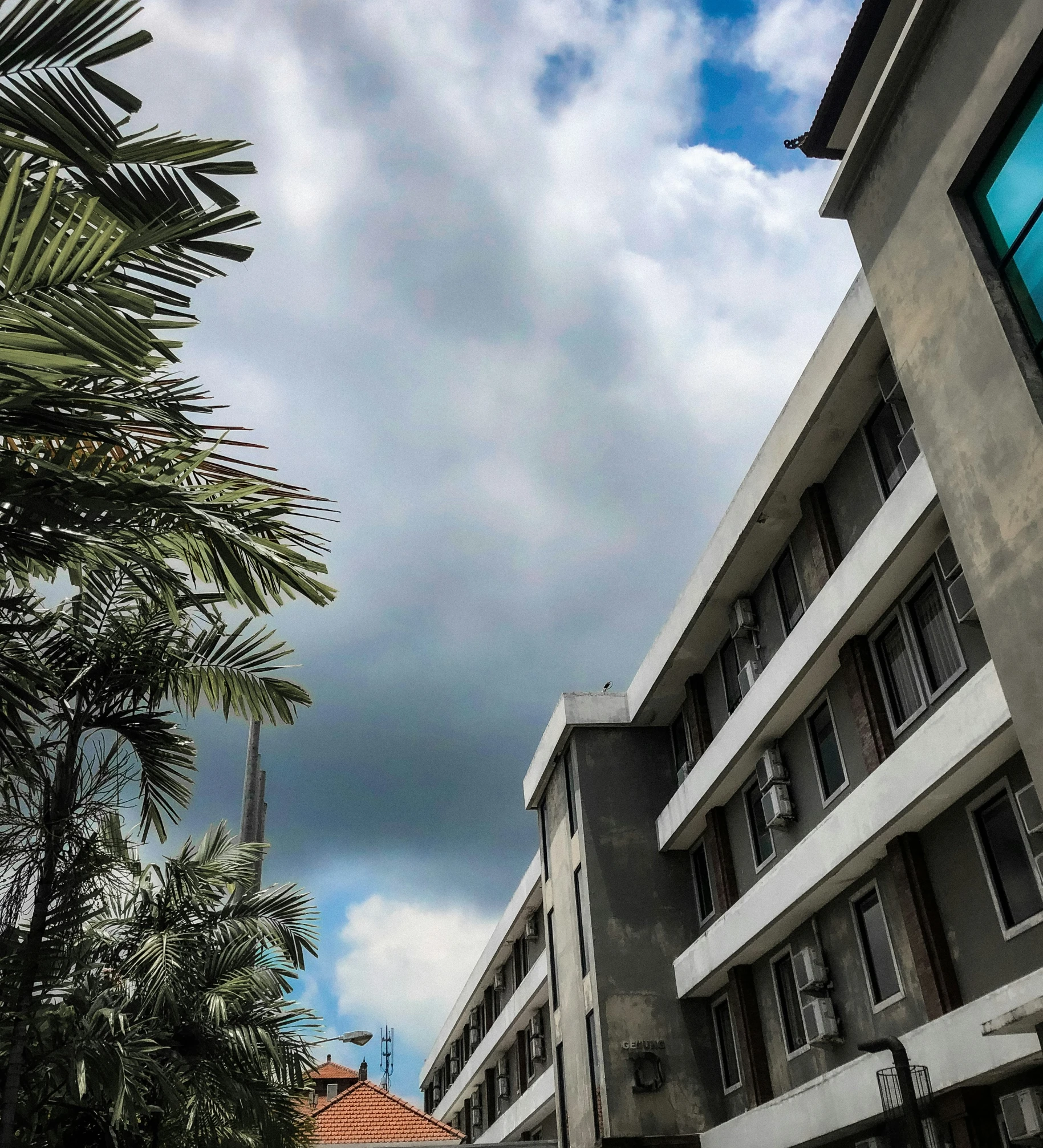 an urban street with tall buildings under a cloudy blue sky