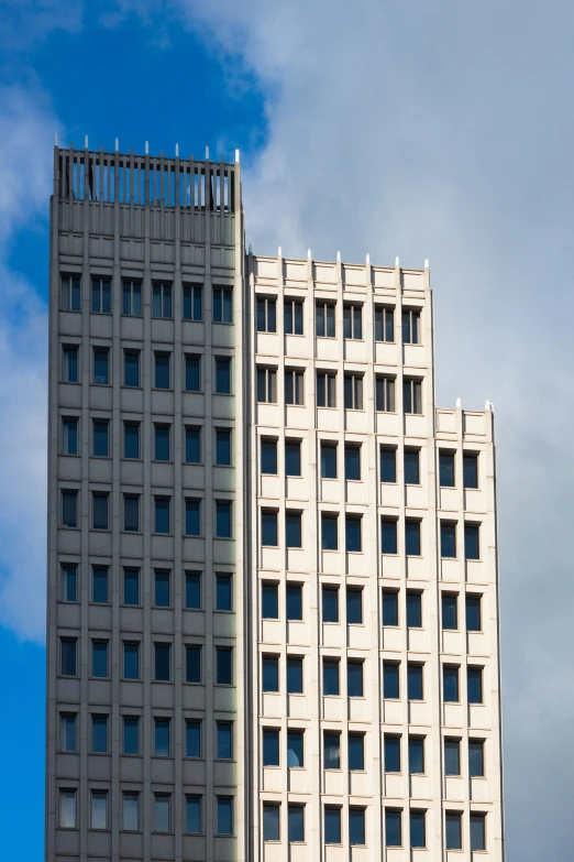 two buildings with windows stand against a blue sky