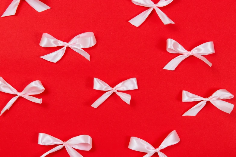 four white bow shapes sit on a red background