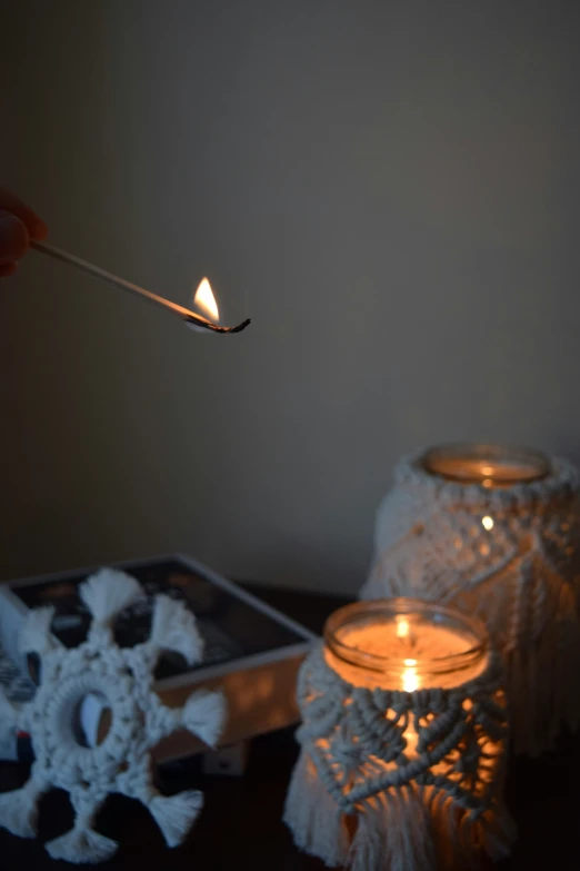 a lit candle is placed next to some lace doily