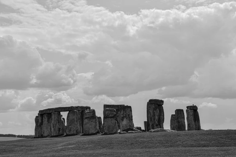 an open field with rock formations with clouds overhead