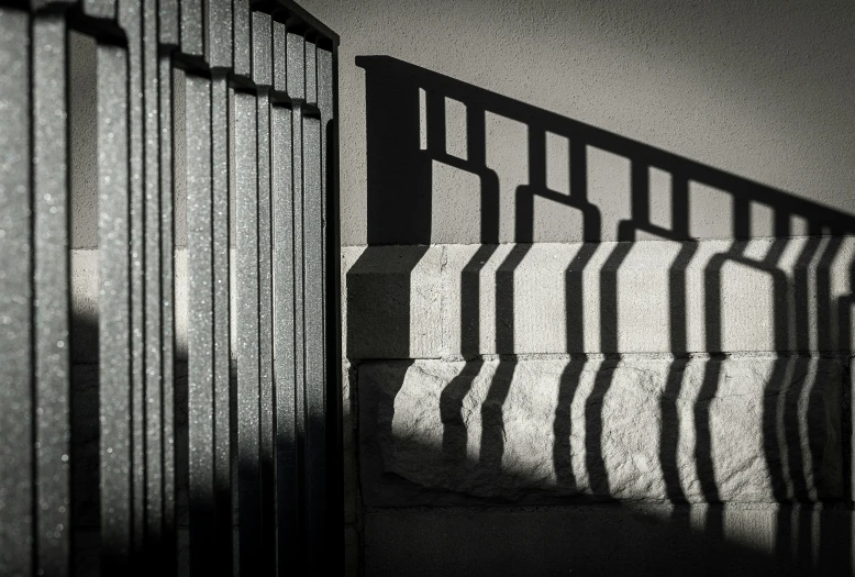 the sun casts on a railing on a wall