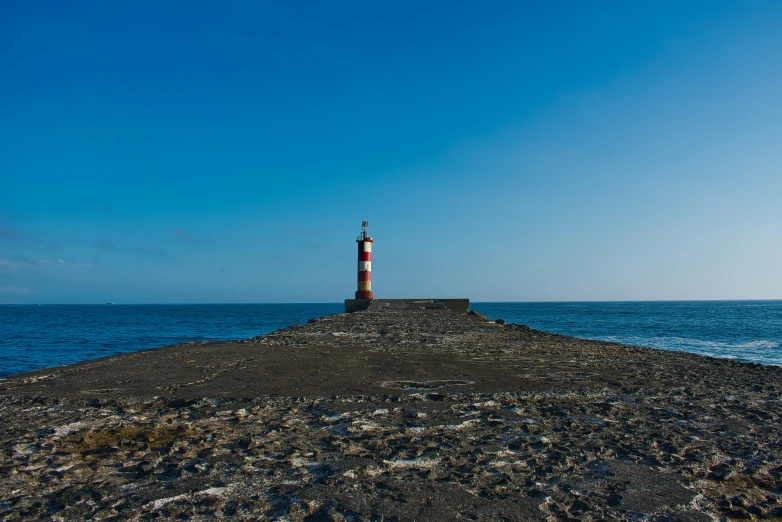 a red and white lighthouse on top of a rocky island