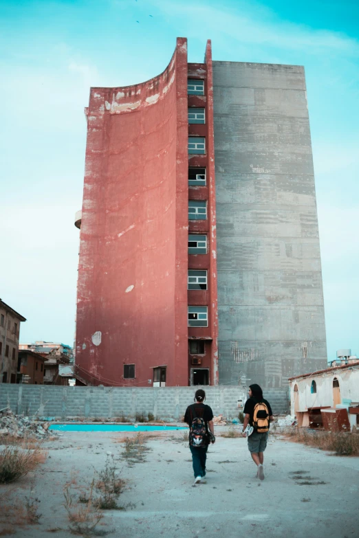 two people walking towards a tall building with a big hole in the middle of it