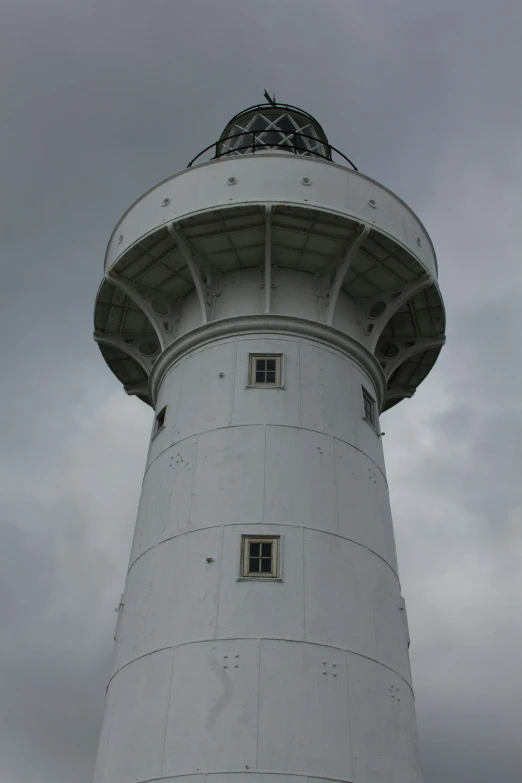 a tall white light house surrounded by clouds