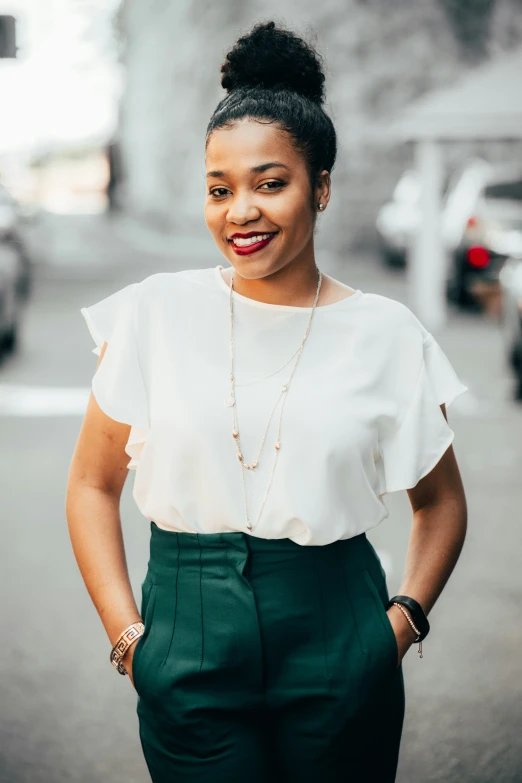 a woman in green pants, a white top and a necklace