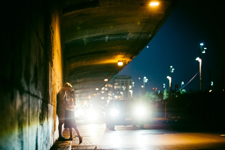 two people stand in a tunnel near parked cars