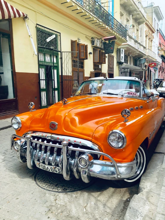 orange and white vintage car parked in front of a building