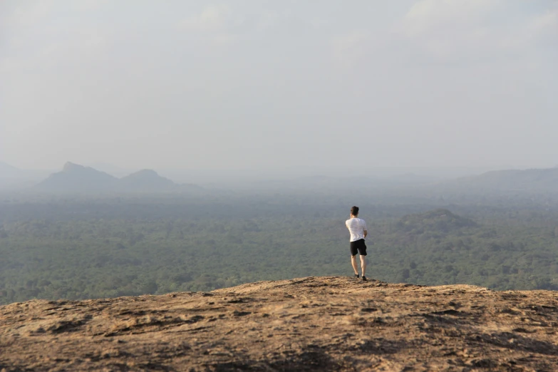 a lone man standing on top of a grass covered hill