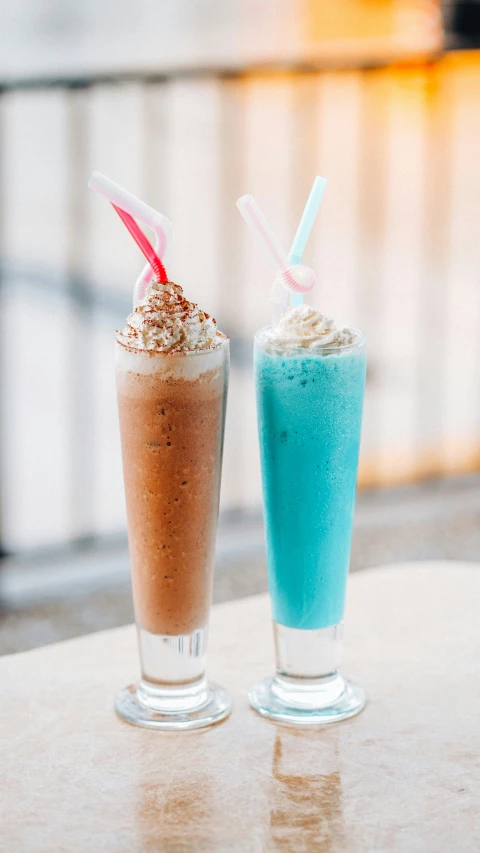 two iced drinks sit on a table next to each other