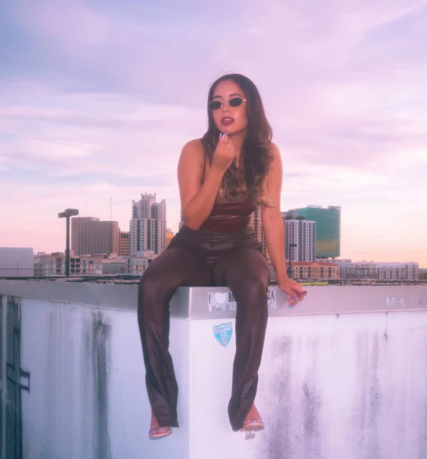 woman in leather outfit smoking cigarette sitting on wall