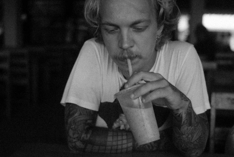 a man with his head up drinking a drink and smoking a cigarette