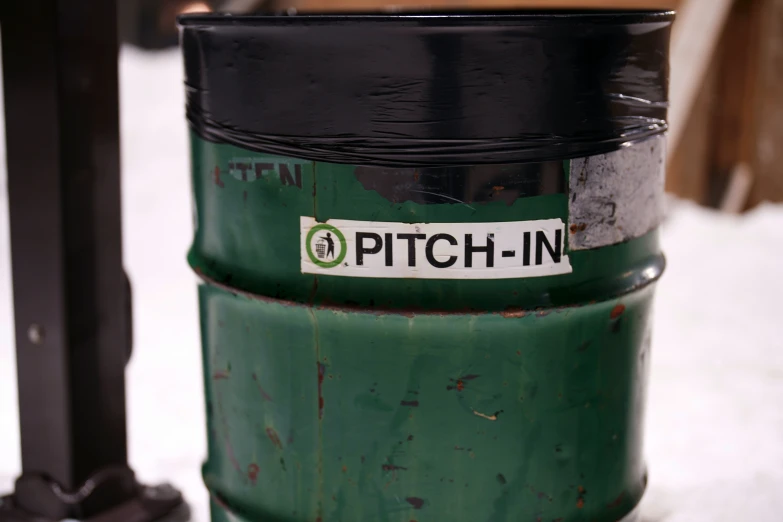 a green and black trash can sitting on a white snow covered ground