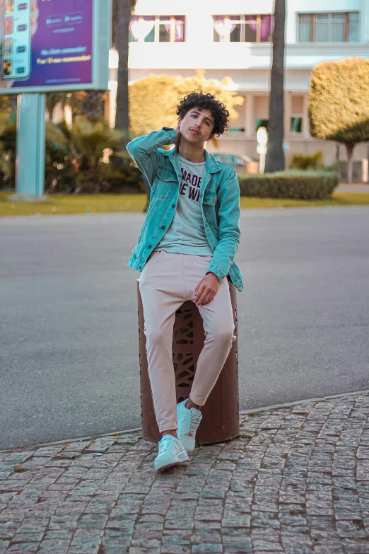 a person sitting on a post next to an asphalted street