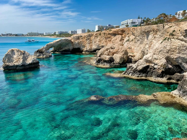 blue waters, rocks, and beach with boats on a sunny day