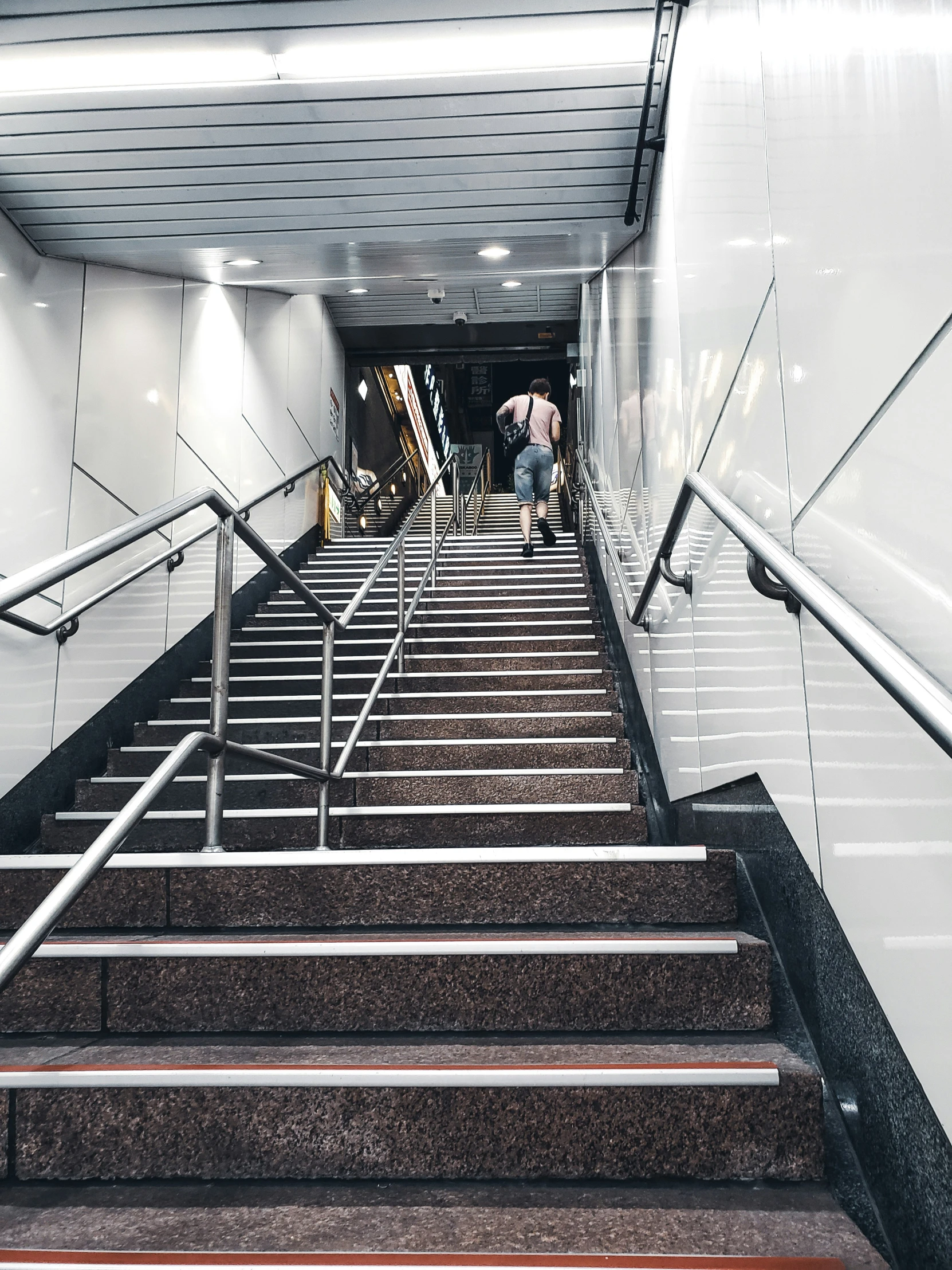 two people are walking down the staircase with one of them using an umbrella