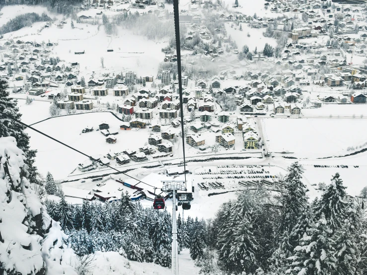 a po taken from a ski lift, with the aerial view of town on a snow - covered hillside