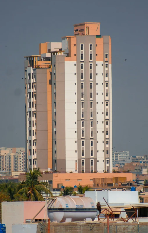 a tall building stands over a city and a few vehicles in front