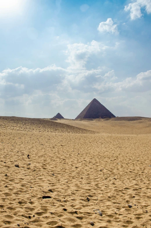 a sandy field with two mountains in the distance