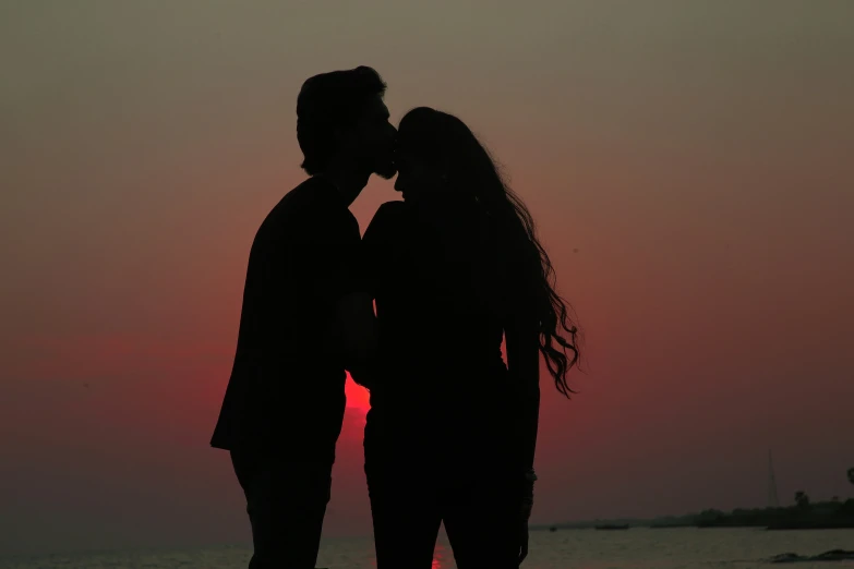 two people are kissing at sunset near the water