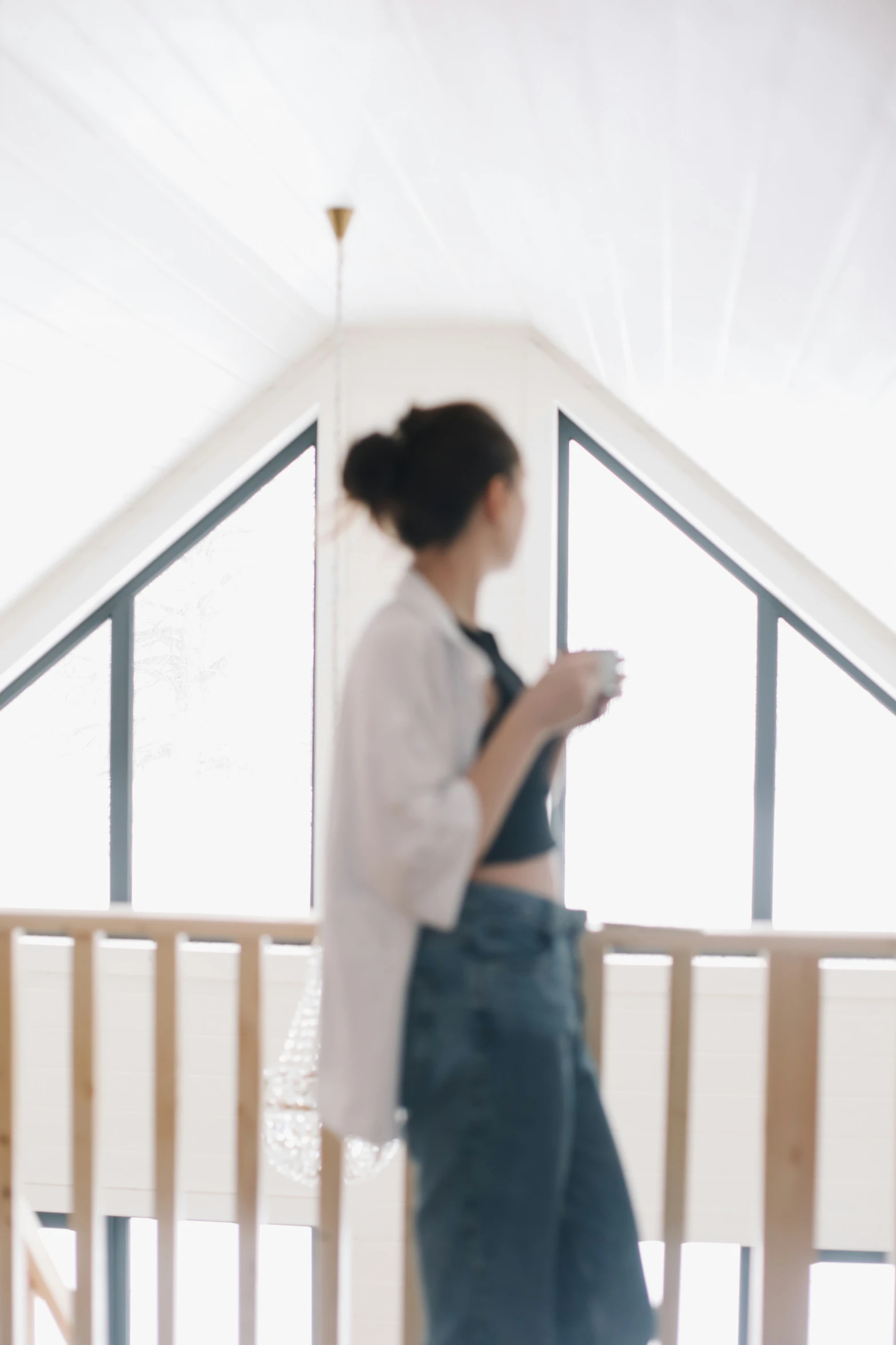 a woman in overalls stands in an upstairs space