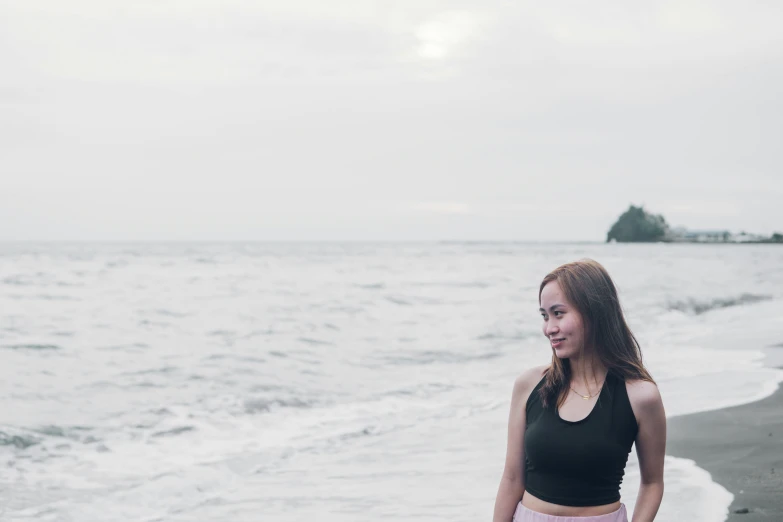 a girl standing on a beach next to the ocean