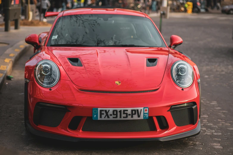 a red porsche is parked near a curb