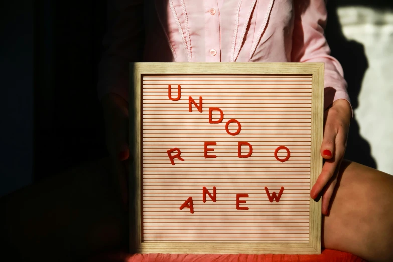 woman showing sign for uno redo new written on wall