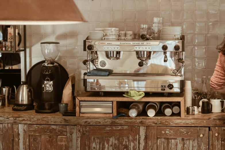 a woman standing next to a coffee machine on top of a wooden counter