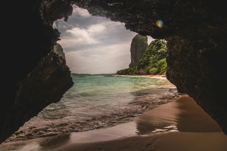 view of an ocean with rocks and water from under a cave